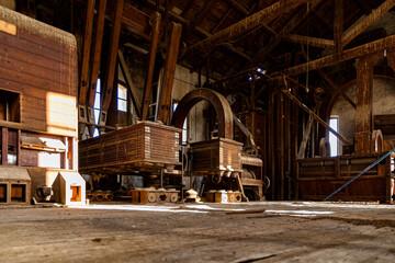 Historical machinery in a deserted warehouse showcasing wooden carts and industrial structure