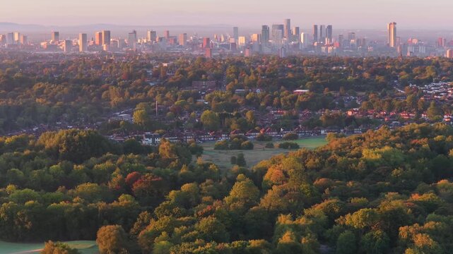 Aerial video of a golden sunrise over Heaton Park fields, woodland, and Manchester city skyline in the distance.