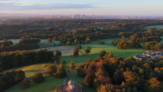 Aerial video of a golden sunrise over Heaton Park fields, woodland, and Manchester city skyline in the distance.