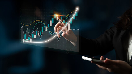 A businessperson utilizes a smartphone while analyzing a dynamic financial chart on a digital interface, representing growth and investment strategies in a modern office setting. Impute