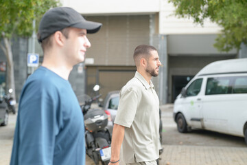 Obraz premium Two men are walking down the street, one wearing a blue shirt and the other wearing a grey shirt