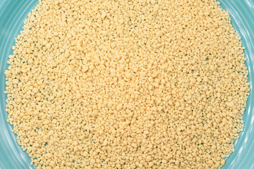 Italian Grattini egg pasta close-up on a blue plate. Small traditional Italian pasta granules used...