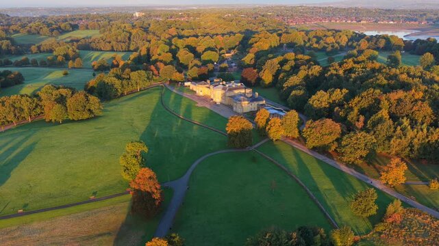 Sunrise aerial video of Heaton Park in Prestwich, Manchester with lush fields, trees, and the temple surrounded by morning light.