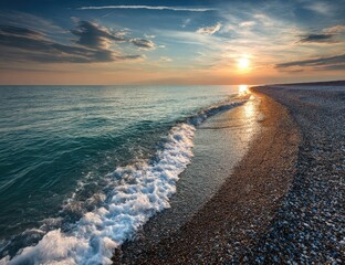 A tranquil coastal scene at sunset, featuring gentle waves lapping at a pebbled beach, showcasing the warm hues of the setting sun.