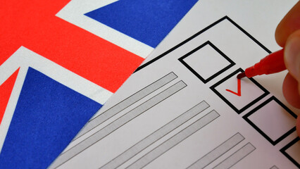 Red marker makes check next to candidate name on ballot. UK elections. Union Jack in background. Voter exercises right to vote in free, fair election process, shaping future through democracy