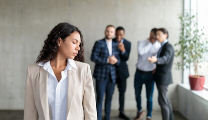 Obraz premium Sexism. Group Of Businessmen Whispering Behind Back Of Victimized Latin Businesswoman In Modern Office. Females Discrimination Problem, Workplace Bullying Concept. Panorama, Selective Focus