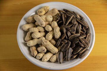 Photograph, Top view of mixed salted peanuts and kuaci (sunflower seeds) served in a plate for snack concept.