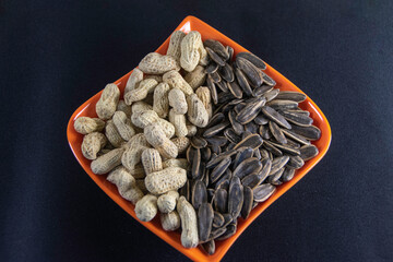 Photograph, Top view of mixed salted peanuts and kuaci (sunflower seeds) served in a plate for...