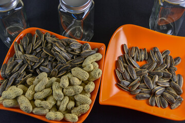 Photograph, Top view of mixed salted peanuts and kuaci (sunflower seeds) served in a plate for snack concept.