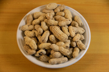 Photograph, one plate of salt peanuts is on a light brown table