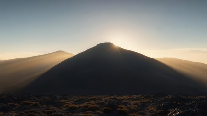 Sunset illuminates a mountain peak, casting long shadows across the landscape
