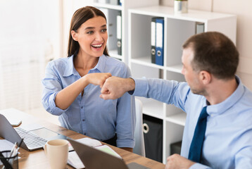 Fototapeta premium Businessman And Businesswoman Bumping Fists Celebrating Business Success At Workplace In Office. Gender Equality And Partnership Concept.