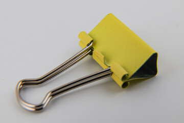 Bright yellow binder clip on a white background for office organization