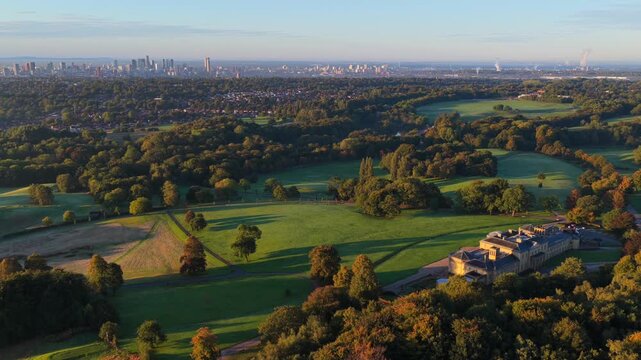 Aerial video of a golden sunrise over Heaton Park fields, woodland, and Manchester city skyline in the distance.