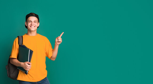 Teen student with books pointing on copy space against turquoise background