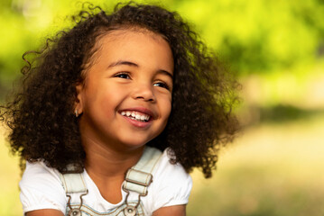 Cute afro girl smiling broadly outdoors, having picnic with parents and enjoying summer day in park