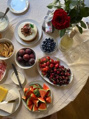 Home breakfast buffet with fruit, cake, roses, and snacks