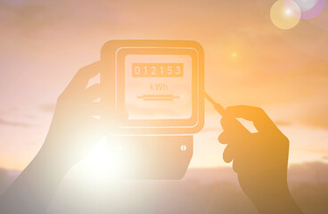 Silhouette of Electric Meter Reading with Hand Holding Screwdriver at Sunset