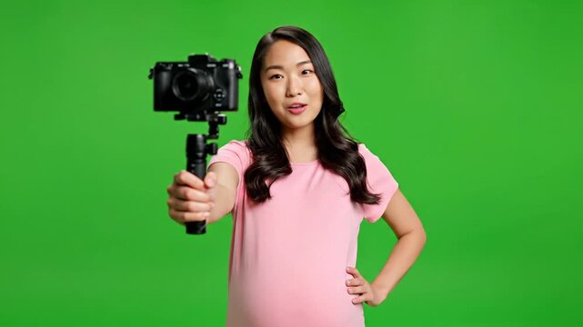Pregnant Asian Vlogger Recording Video with Camera on Green Screen.