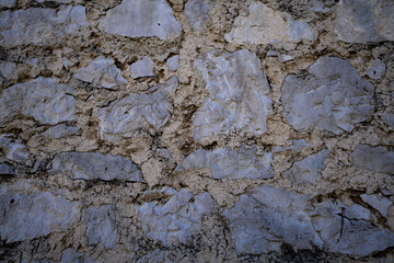 Stone background with natural texture. Rustic stone wall background for design. Close-up of textured stone surface background. Decorative stone facade as background.
