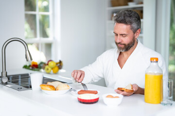 Middle aged Man eat breakfast in the kitchen on a morning. Guy eat vegetables for a healthy meal in his kitchen in the morning. Cozy kitchen. Morning breakfast in the modern kitchen.