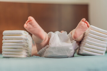 Baby lying between two stacks of diapers. Concept of diaper quality, cost, and baby care essentials. Parenthood, budgeting, and infant hygiene themes