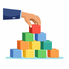 Fototapeta premium Hand Placing Colorful Building Block on Top of a Stacked Pyramid Against White Background
