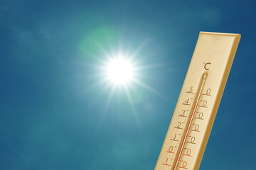 Thermometer showing high temperature against sky with bright sun. Extremely hot weather