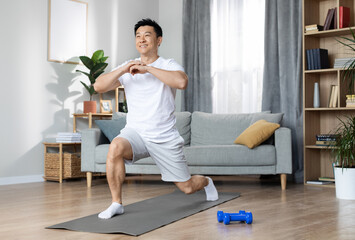 Athletic handsome middle aged asian man in white sportswear training alone at home, exercising on fitness mat, having morning yoga workout, copy space, full length shot
