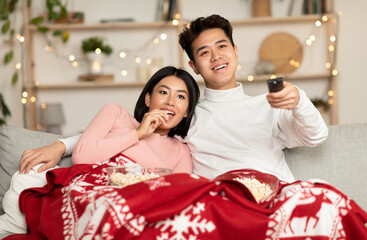 Japanese Couple Watching TV On Christmas Eve Enjoying Family Movies And Eating Popcorn Sitting On...