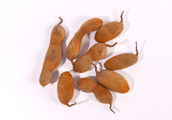 A pile of whole, ripe tamarind pods (Tamarindus indica) isolated on a white background. This...
