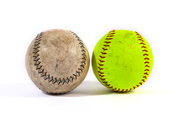 An old, vintage baseball and a modern yellow softball are placed side-by-side. Isolated on a white background, this image compares the equipment from two similar sports.