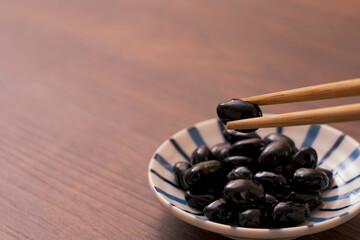 A traditional dish made for Japanese New Year's celebrations. Boiled black beans.正月などに作られる日本の伝統的な料理。黒豆の煮豆。