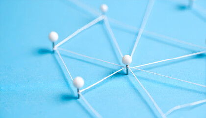 Network connection with white pin and strings on blue background symbolizing teamwork, and relationship connections.
