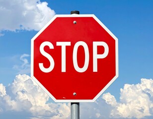 Obraz premium Red octagonal stop sign against a blue sky with fluffy white clouds
