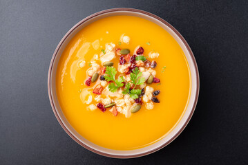 Top view of Butternut squash pumpkin soup with granola in a bowl on black background, Homemade food in autumn season