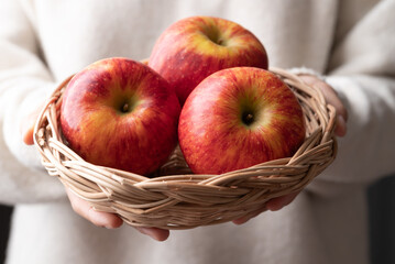 Red apple fruit (Envy apple) in basket hoding by woman hand