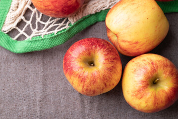 Top view of red apple fruit (Envy apple) with mesh bag on brown fabric background