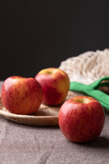 Red apple fruit (Envy apple) in basket on brown fabric with black background
