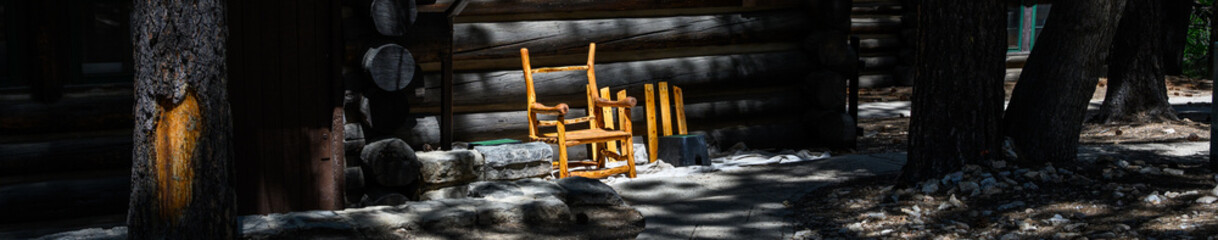 Furniture repair and maintenance, fixing rustic wood branch rocking chair outside classic log cabin, north rim Grand Canyon National Park, Arizona
