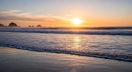 Golden hour sunset over gentle ocean waves reflecting light on sandy beach