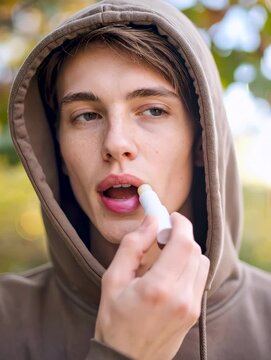 Hombre aplicando b&aacute;lsamo labial con capucha