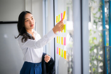 Businesswoman developing project strategy using sticky notes on glass