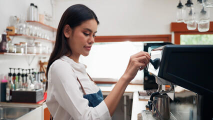 Young Asian woman barista is using a coffee maker. Bakery cafe and coffee shop small business owner concept