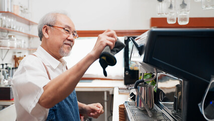 Senior Asian man barista is using a coffee maker. Bakery cafe and coffee shop small business owner concept