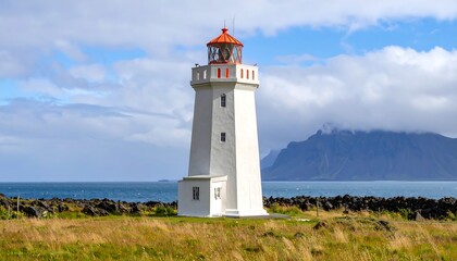 Coastal lighthouse, white structure, orange roof, scenic ocean view, mountainous backdrop