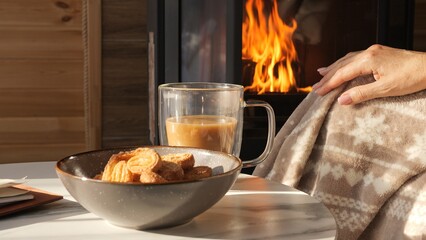 Slow living moment near fireplace with cozy blanket glowing flames and mindful aromatic coffee break Coffee aroma creates warmth cookies and coffee bring peaceful comfort symbol of winter relaxation