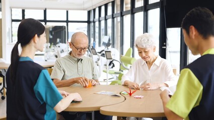 介護施設で折り紙を折るアジア人高齢者