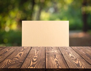 Rustic wood plank table with a blank cardboard sign for product display against a blurred green nature background
