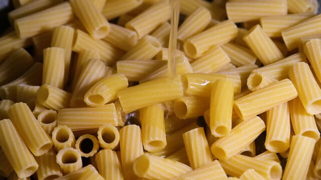 Pouring water into a pot to cook pasta. Cooking preparation &mdash; Pouring water for boiling pasta. Home cooking process &mdash; Boiling water for pasta.